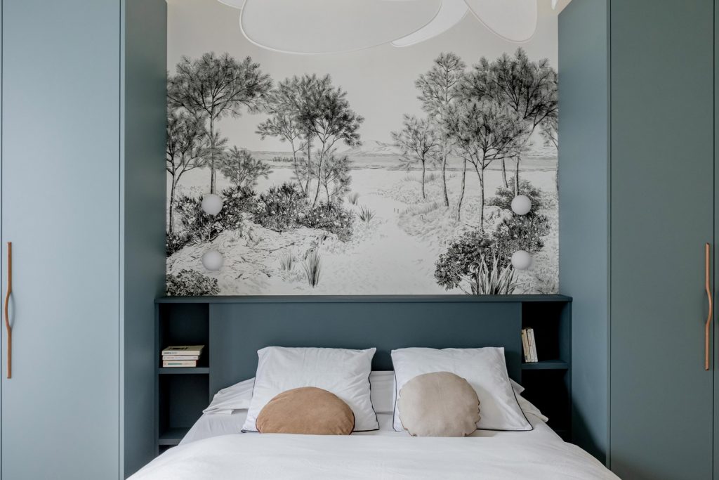 Tête de lit bleue entourée de deux dressings et un papier peint nature