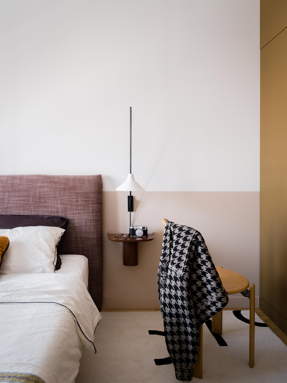 Chambre avec mur bicolore, applique design, chevet suspendu et placards kaki.