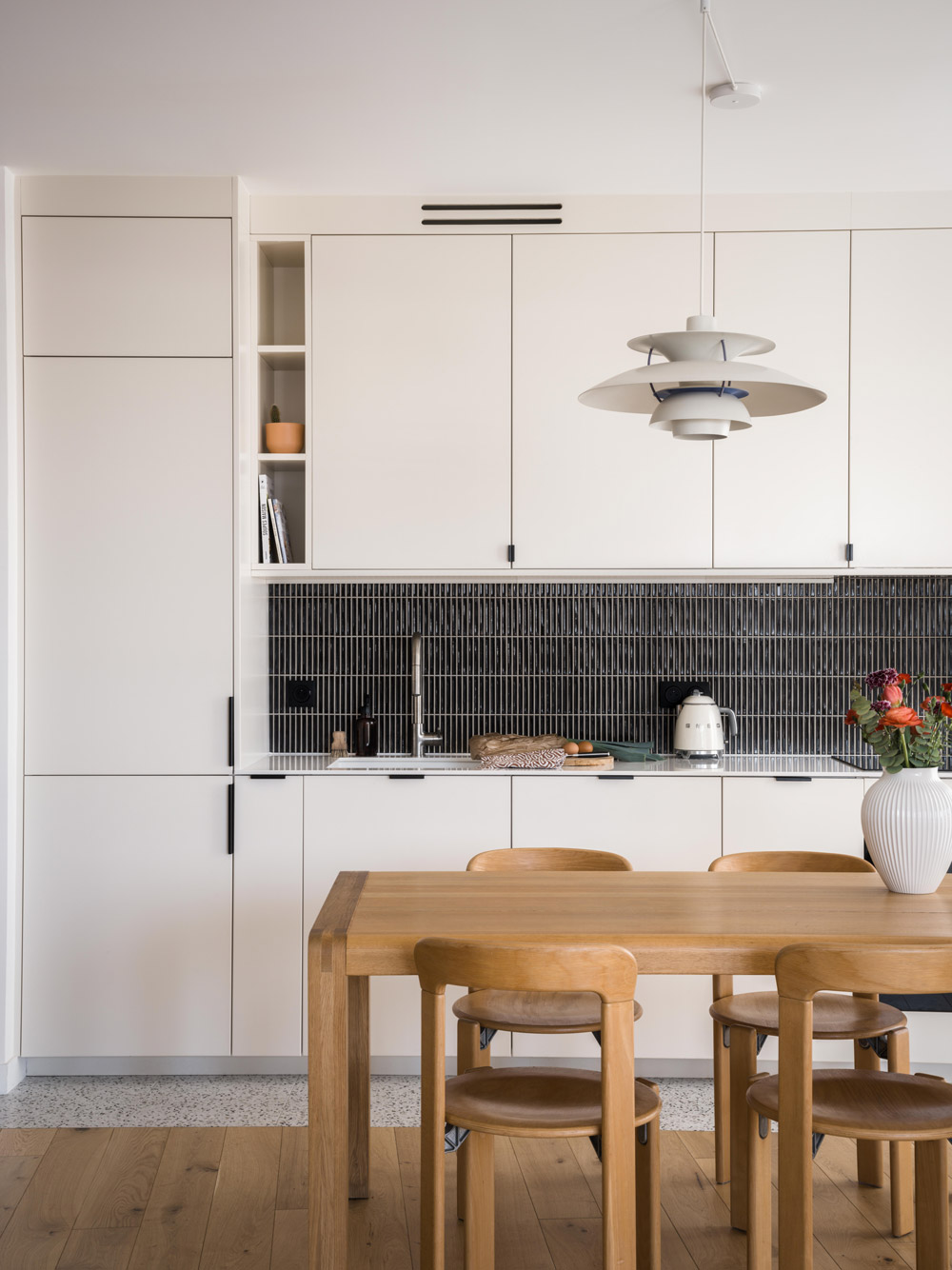 Cuisine sur mesure blanche avec crédence foncée, table en bois et suspension design.