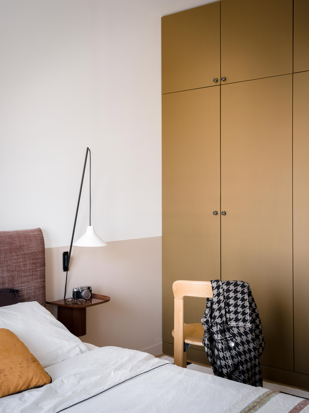 Chambre avec placards sur mesure bronze, tête de lit textile et mur bicolore.